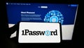 Person holding smartphone with logo of password manager company AgileBits Inc. (1Password) on screen with website.