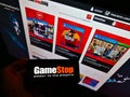 Person holding smartphone with logo of retail company GameStop Corp. in front of website with online shop.