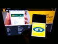 Person holding smartphone with logo of South African telecommunications company MTN Group on screen in front of website. Royalty Free Stock Photo