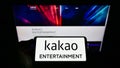 Person holding smartphone with logo of South Korean company Kakao Entertainment Corp. on screen in front of website.