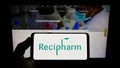 Person holding smartphone with logo of Swedish pharmaceutical Recipharm AB on screen in front of website.