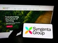 Person holding smartphone with logo of Swiss agriculture company Syngenta Group on screen in front of website. Royalty Free Stock Photo