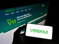 Person holding smartphone with logo of Swiss IT company Veeam Software Group GmbH on screen in front of website.