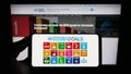 Person holding smartphone with logo of UN Sustainable Development Goals (SDG) on screen in front of website.