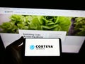 Person holding smartphone with logo of US agricultural chemical company Corteva Inc. on screen in front of website.