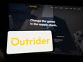 Person holding smartphone with logo of US company Outrider Technologies Inc. on screen in front of website. Royalty Free Stock Photo