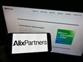 Person holding smartphone with logo of US consulting firm AlixPartners LLP on screen in front of website.