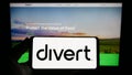 Person holding smartphone with logo of US food technology company Divert Inc. on screen in front of website.