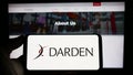 Person holding smartphone with logo of US gastronomy company Darden Restaurants Inc. on screen in front of website.