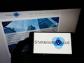 Person holding smartphone with logo of US hedge fund Starboard Value LP on screen in front of website.