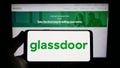 Person holding smartphone with logo of US job review company Glassdoor Inc. on screen in front of website. Royalty Free Stock Photo