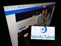 Person holding smartphone with logo of US learning platform Varsity Tutors operated by Nerdy Inc. on screen.