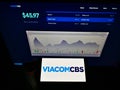 Person holding smartphone with logo of US mass media company ViacomCBS Inc. on screen in front of website.