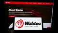 Person holding smartphone with logo of US rail manufacturing Wabtec Corporation on screen in front of website.