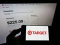 Person holding smartphone with logo of US retail company Target Corporation on screen in front of website.