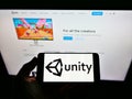 Person holding smartphone with logo of US video game company Unity Software Inc. on screen in front of website. Royalty Free Stock Photo