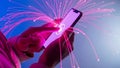 A person holding a smartphone with pink light trails and sparks emanating from it Royalty Free Stock Photo