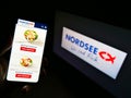 Person holding smartphone with products of German fast-food restaurant chain Nordsee GmbH on display in front of company logo.