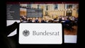 Person holding smartphone with seal of German legislative body Bundesrat on screen in front of website.