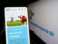 Person holding smartphone with web page of company Koninklijke FrieslandCampina N.V. on screen in front of logo.
