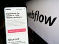 Person holding smartphone with web page of US web development software company Webflow Inc. on screen with logo. Royalty Free Stock Photo