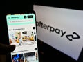 Person holding smartphone with webpage of Australian fintech company Afterpay Limited on screen in front of business logo.