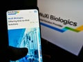 Person holding smartphone with webpage of biotechnology company WuXi Biologics (Cayman) Inc. on screen with logo.