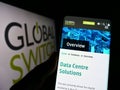 Person holding smartphone with webpage of British data center company Global Switch Ltd. on screen with logo.