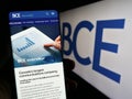 Person holding smartphone with webpage of Canadian telecommunications company BCE Inc. on screen with logo.