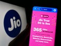 Person holding smartphone with webpage of Indian telecommunications company Reliance Jio on screen with logo.