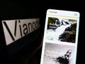 Person holding smartphone with webpage of Norwegian battery materials company Vianode on screen with logo.