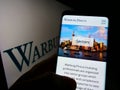 Person holding smartphone with webpage of US private equity company Warburg Pincus LLC on screen with logo.