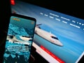 Person holding smartphone with website of aircraft manufacturer Avions de Transport RÃÂ©gional (ATR) on screen.