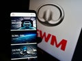 Person holding smartphone with website of car manufacturer Great Wall Motors Co. Ltd. (GWM) on screen with logo.