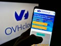 Person holding smartphone with website of French cloud computing company OVH Groupe SAS on screen in front of logo.