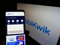 Person holding smartphone with website of Indian financial technology company MobiKwik on screen in front of logo.
