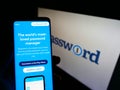 Person holding smartphone with website of password manager company AgileBits Inc. (1Password) on screen with logo.