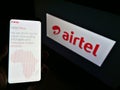 Person holding smartphone with website of telecommunications provider Airtel Africa plc in front of business logo.