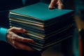 Person holding a stack of organized blue folders in a dimly lit workspace. Generative AI