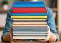 Person holding a tall stack of colorful books ready for learning Royalty Free Stock Photo