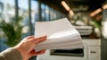 Person holding a thick stack of blank white printer paper ready for copying or printing in an office environment with modern Royalty Free Stock Photo