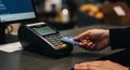 A person holds a blue credit card, tapping it on a digital payment terminal