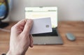 Person holds credit card in front of computer for online transaction Royalty Free Stock Photo