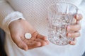 Person holds a glass of water with a round white tablet in hand Royalty Free Stock Photo