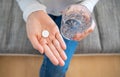 Person holds a glass of water with a round white tablet in hand Royalty Free Stock Photo