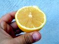 A person holds half a lemon between his fingers