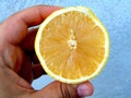 A person holds half a lemon between his fingers