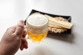 Person holds a mug of unfiltered light wheat beer, beer snacks on white table Royalty Free Stock Photo