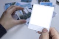 A person holds a polaroid photo in his hands against the background of other photos. Photo in hand close-up. Royalty Free Stock Photo