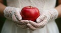 A person holds a shiny red apple with both hands.